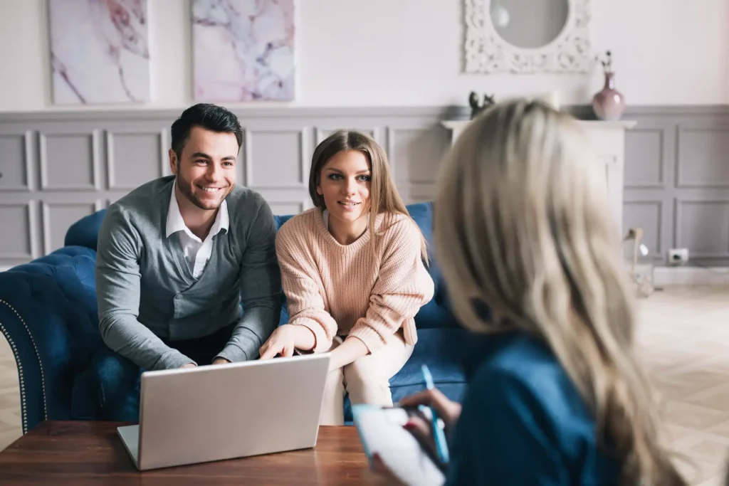 a group of people sitting on a sofa looking at a laptop